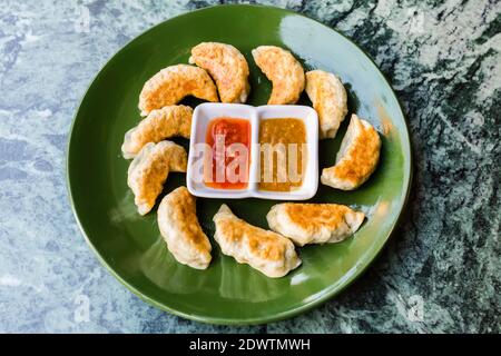 Nepalesischer gebratener Knödel momo serviert mit Tomatenchutney. Traditionelles asiatisches Essen, Blick von oben Stockfoto