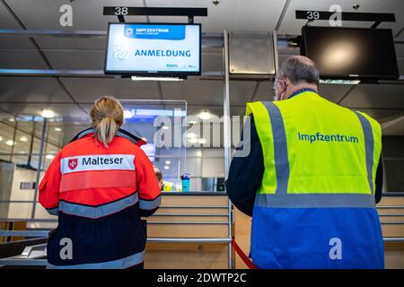 Greven, Deutschland. Dezember 2020. Ein Helfer des Malteser Hilfsdienstes steht am Meldeschalter im Terminal am Flughafen Münster-Osnabrück neben einem Mitarbeiter der Impfstelle des Kreises Steinfurt. Am Flughafen startete im Impfzentrum ein Testlauf mit rund 50 Testpersonen aus THW, DLRG, Malteser, DRK Kreisverband ST und DRK Kreisverband TE. Quelle: Guido Kirchner/dpa/Alamy Live News Stockfoto