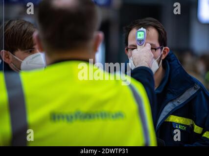 Greven, Deutschland. Dezember 2020. Ein Mitarbeiter der Impfstelle des Landkreises Steinfurt misst im Terminal am Flughafen Münster-Osnabrück die Körpertemperatur an der Stirn einer Testperson des Technischen Hilfswerks (THW). Am Flughafen startete im Impfzentrum ein Testlauf mit rund 50 Probanden aus THW, DLRG, Malteser, DRK Kreisverband ST und DRK Kreisverband TE. Quelle: Guido Kirchner/dpa/Alamy Live News Stockfoto