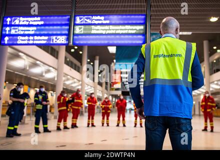 Greven, Deutschland. Dezember 2020. Helfer des Deutschen Roten Kreuzes stehen im Terminal am Flughafen Münster-Osnabrück und erhalten Anweisungen von einem Mitarbeiter der Kreisimpfungsstelle Steinfurt. Am Flughafen Münster-Osnabrück startete im Impfzentrum ein Testlauf mit rund 50 Probanden von THW, DLRG, Malteser, DRK Kreisverband ST und DRK Kreisverband TE. Quelle: Guido Kirchner/dpa/Alamy Live News Stockfoto