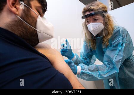 Greven, Deutschland. Dezember 2020. Anja Büscher (r), medizinische Assistentin des Verbandes der gesetzlichen Krankenversicherungsärzte, legt zu Testzwecken eine Spritze auf den Arm von Leon Berisa vom Technischen Hilfswerk (THW) im Impfzentrum des Kreises Steinfurt. Am Flughafen des Impfzentrums startete ein Testlauf mit rund 50 Testpersonen aus THW, DLRG, Malteser, DRK Kreisverband ST und DRK Kreisverband TE. Quelle: Guido Kirchner/dpa/Alamy Live News Stockfoto