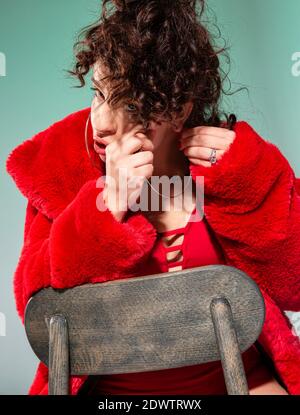Europäische weiße Frau in roten Kleidern mit der Hand in der Nähe der Teilfläche isoliert auf grün Stockfoto