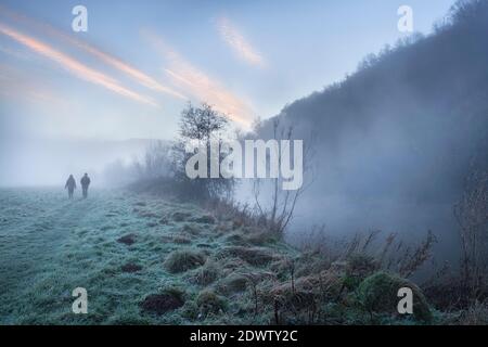 Zwei Menschen, die an einem nebligen Morgen am Brockweir entlang des Flusses Wye spazieren. Stockfoto