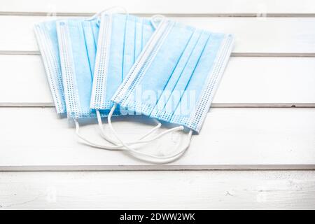 Drei blaue Schutzmasken auf weißem Holzhintergrund, Nahaufnahme. Stockfoto