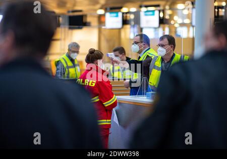 Greven, Deutschland. Dezember 2020. Ein Mitarbeiter des Impfzentrums des Landkreises Steinfurt misst die Körpertemperatur an der Stirn einer Testperson der Deutschen Lebensrettergesellschaft (DLRG) im Terminal am Flughafen Münster-Osnabrück. Am Flughafen startete im Impfzentrum ein Testlauf mit rund 50 Probanden aus THW, DLRG, Malteser, DRK Kreisverband ST und DRK Kreisverband TE. Quelle: Guido Kirchner/dpa/Alamy Live News Stockfoto