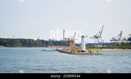 Touristen am Mühlenfeuer, dem Wahrzeichen der Stadt Swinoujscie, im Hintergrund der Hafen Stockfoto