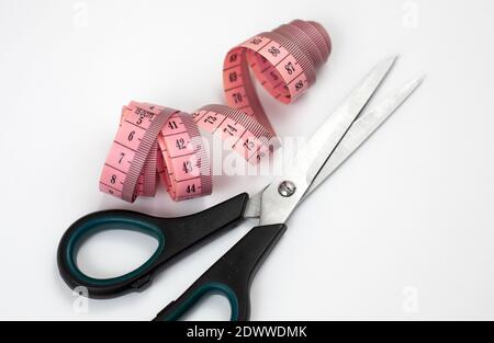 Schere und rosa Maßband auf weißem Hintergrund Stockfoto