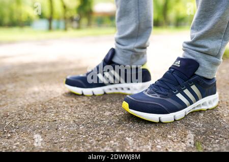 UKRAINE, ZAPOROZHYE - MAI 24, 2020 : männliche Füße in blauen Adidas-Schuhe im Freien Stockfoto