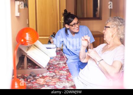 Glückliche ältere Frau mit ihrem Betreuer zu Hause. Pflegekonzept für Senioren. Stockfoto