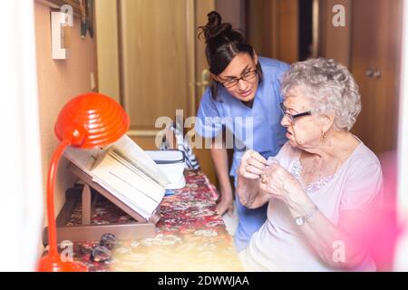 Verärgerte ältere Frau mit ihrem Betreuer zu Hause. Pflegekonzept für Senioren. Stockfoto