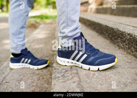 UKRAINE, ZAPOROZHYE - MAI 24, 2020 : männliche Füße in blauen Adidas-Schuhe im Freien Stockfoto