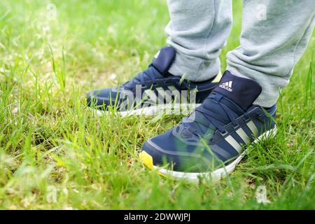 UKRAINE, ZAPOROZHYE - MAI 24, 2020 : männliche Füße in blauen Adidas-Schuhe im Freien Stockfoto