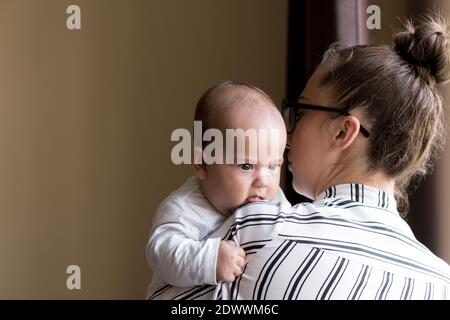 Kindheit, Mutterschaft, Familienkonzepte - erfolgreich lächelnd reiche Geschäftsfrau Lady Mutter hält Säugling Kind neugeborenes Baby in ihren Händen steht und Stockfoto