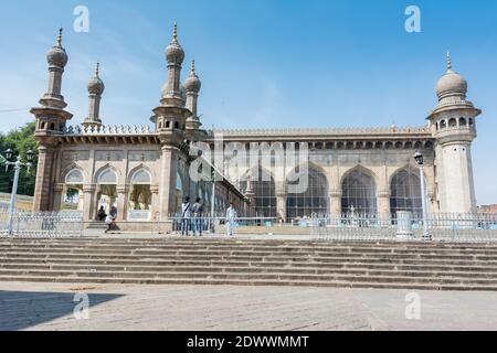 Muslimische Pilger, die in die Moschee Mekka Masjid gegen blauen Himmel und Tauben fliegen in Himmel, ein berühmtes Denkmal in Hyderabad Stockfoto