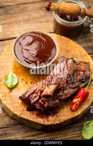 Köstliche BBQ Baby-back Rippen mit würzigen Sauce und einem Pinsel auf Holz Schneidebrett Stockfoto