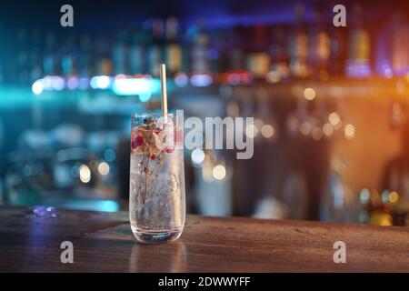 Moderner Gin Tonic Cocktail mit Eis, Stroh und roten Beeren an der Theke Stockfoto