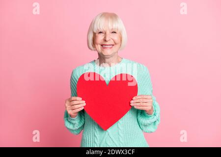 Foto-Porträt von niedlichen Großmutter halten rote Herz Symbol Liebe isoliert auf pastellrosa Hintergrund Stockfoto