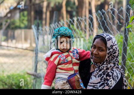 Eine indische muslimische Mutter lächelt und hält ihr Baby und grüßt Touristen im Nehru Zoological Park, hyderabad Indien Stockfoto