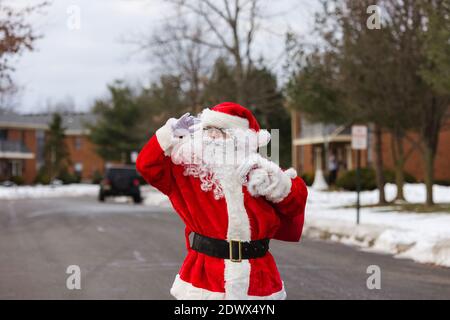 Schnee Weihnachtsmann zu Fuß entlang der Straße trägt eine große Beutel mit Geschenken auf Bäumen mit Schnee bedeckt Stockfoto