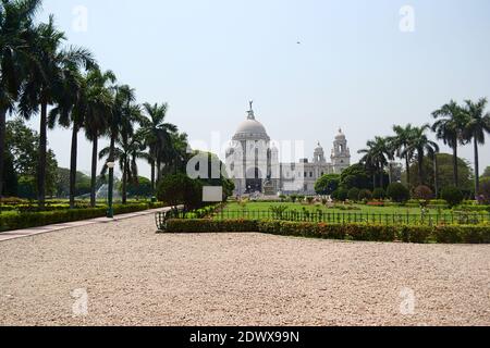 Victoria Memorial historisches Gebäude in Kalkutta. Grüne Gärten im Park und tropische Palmen entlang Gehwege. Kolkata, Westbengalen, Indien Stockfoto