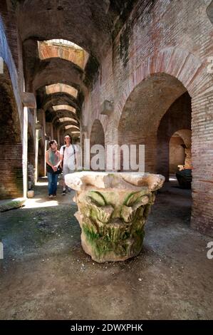 Riesige alte römische Hauptstadt einer Säule mit Touristen zu Fuß vorbei, im Flavian Amphitheater. Pozzuoli, Campi Flegrei (Phlegräische Felder), Neapel Stockfoto