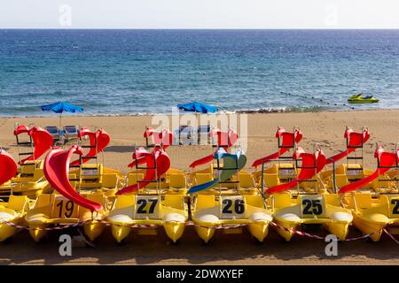 Bunte Tretboote mit Rutsche am leeren Strand in Puerto del Carmen, Lanzarote. Tourismus-Krise, Pandemie Lockdown Folgen, Sommer Erholung Stockfoto