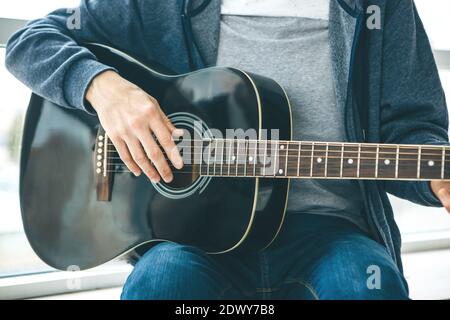 Der Gitarrist spielt Gitarre. Oder eine Person lernt, Gitarre zu spielen. Stockfoto