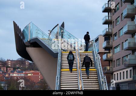 Eine Fußgängerbrücke über die Eisenbahn in Lincolns Brayford Wharf East. Fußgänger können gesehen werden, wie sie über die Brücke fahren, wenn ein Zug darunter vorbeifährt. Die Brücke verbindet den Universitätskomplex mit dem Stadtzentrum, wenn Züge fahren und die Bahnübergänge herunterfahren. Stockfoto