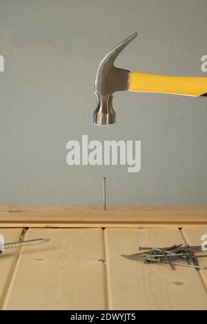 Hammer Schlägt Nagel Auf Den Kopf. DIY. Zimmermannshand mit Hammerholz und Nagel. Mit Hammer auf Holz Hintergrund. Werkzeuge für Hausreparatur. Reparieren Sie das Haus. Stockfoto