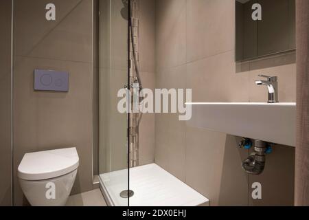 Moderne Einrichtung eines kleinen, modernen Badezimmers mit weißen Sanitär- und Dekoration durch graue Mosaiksteinfliesen Stockfoto