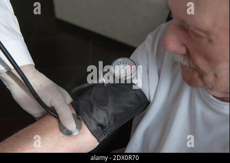 Nahaufnahme eines Arztes mit einem Stethoskop am Ellenbogen einer älteren Person, um den Blutdruck zu messen. Ein Gerontologe überwacht die Gesundheit eines älteren Pat Stockfoto