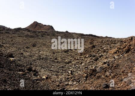 Schwarze Felsen mit Vulkan auf der Spitze des Timanfaya National Park. Vulkanische Naturlandschaft auf der Insel Lanzarote. Touristenattraktion, Reisekonzepte Stockfoto