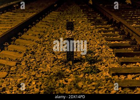 Zwei Gleise und ein Bahnstock schwarz mit einem Weißer Streifen und ein gemahlener Glasstein Stockfoto