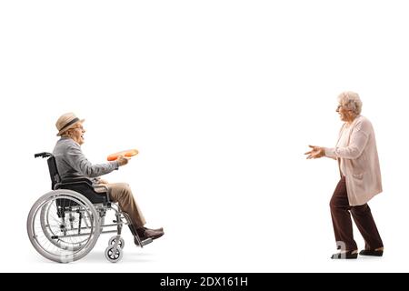In voller Länge Profilaufnahme eines älteren Mannes in einem Rollstuhl wirft eine Plastikscheibe zu einer älteren Frau isoliert Auf weißem Hintergrund Stockfoto