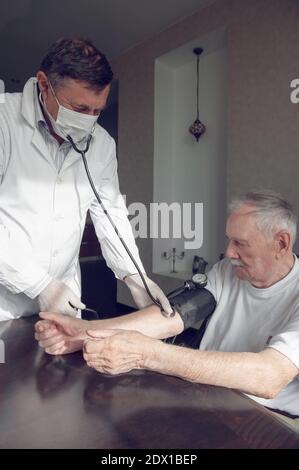 Nahaufnahme eines Arztes mit einem Stethoskop am Ellenbogen einer älteren Person, um den Blutdruck zu messen. Ein Gerontologe überwacht die Gesundheit eines älteren Pat Stockfoto