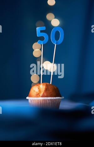 Geburtstag Cupcake oder Muffin mit der Nummer fünfzig (50) und Lichter auf dem blauen Hintergrund. Geburtstags- oder Jubiläumskonzept Stockfoto