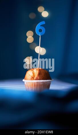 Geburtstag Cupcake oder Muffin mit Nummer sechs (6) und Lichter auf dem blauen Hintergrund. Geburtstags- oder Jubiläumskonzept Stockfoto