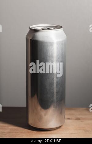 Geschlossene glänzende Aluminium-Dose steht auf einem Holztisch, Standard-Softdrink-Verpackung, vertikales Foto Stockfoto