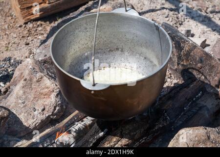 Gehackte weiße Zwiebel in einem Kessel rösten. Vorbereitung der Mahlzeit auf dem offenen Feuer Stockfoto