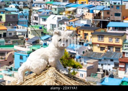 Eine Katzenstatue auf Strohdach mit Gamcheon-Kulturdorf im Hintergrund in Busan. Stockfoto