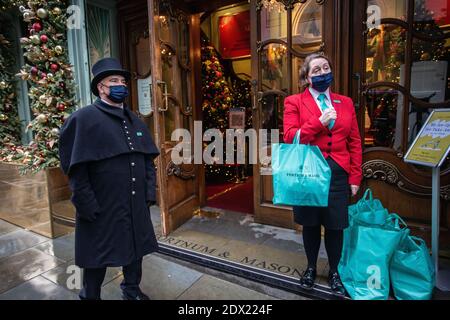 England/London/Piccadilly/Türsteher mit Gesichtsmaske wegen der COVID-19 Pandemie, am 23. Dezember 2020 bei Fortnum & Mason in London. Stockfoto