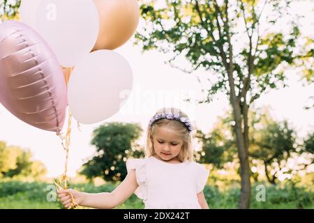 Kleine glänzende Mädchen mit rosa Ballons im Garten Stockfoto