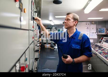 Marine Engineer Officer Steuerung von Schiffsmotoren und Antrieb in Motor Kontrollraum Stockfoto