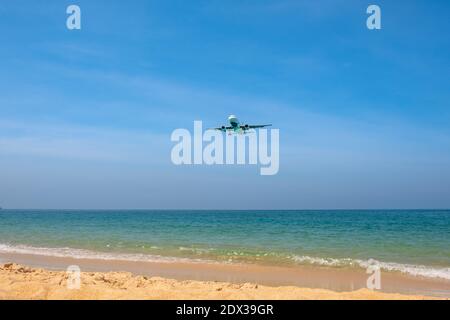 Das Flugzeug kommt für die Landung fliegen über einen schönen tropischen Strand mit feinem Sand und blauem Meer. Stockfoto