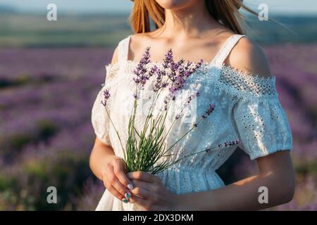 Nahaufnahme eines Mädchens in einem weißen Kleid mit einem Ein Strauß Lavendel in ihren Händen Stockfoto