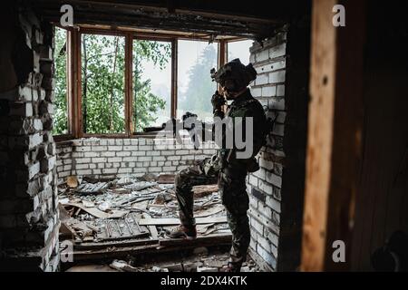 Waffeninspektion während des Wartens an einer Stelle. Militärmann überprüft sein Sturmgewehr, um sich auf den Betrieb vorzubereiten. Stockfoto