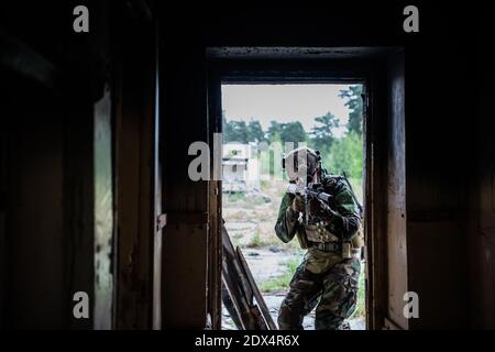 Soldat in voller US-MARSOC-Ausrüstung in verlassene Gebäude betreten, mit verschiedenen Winkeln mit MK18 Sturmgewehr zielen Stockfoto