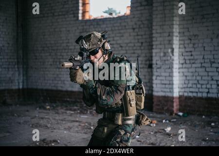 Soldat in voller US-MARSOC-Ausrüstung in verlassene Gebäude betreten, mit verschiedenen Winkeln mit MK18 Sturmgewehr zielen Stockfoto