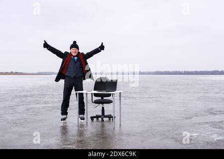 Geschäftsmann im Anzug steht mit ausgestreckten Händen an einem Tisch In der Mitte See Stockfoto