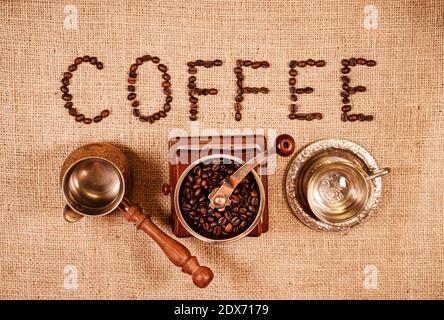 Geröstete Kaffeebohnen in Buchstaben angeordnet Kaffee mit Mahlwerk. Stockfoto